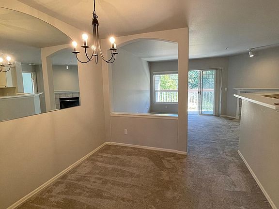 Dining room with living room beyond the half-wall and kitchen to the right.