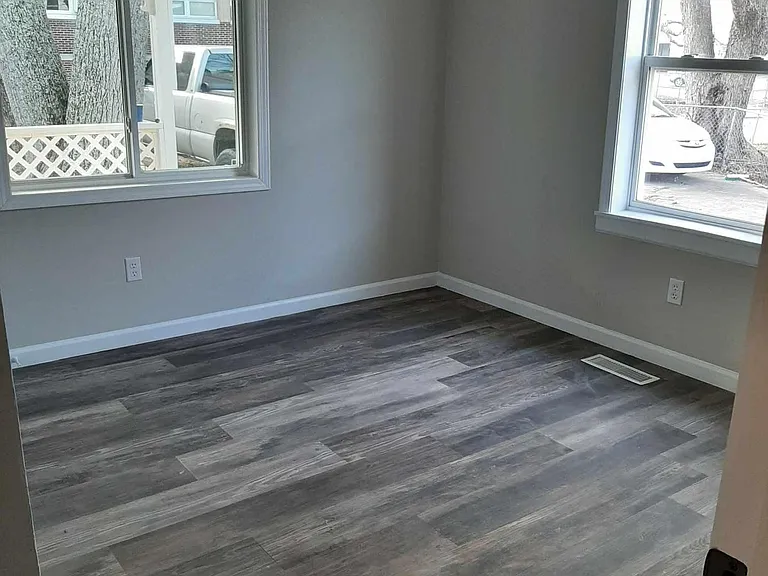 Front of house bedroom with 2 windows and closet. Closet has light and bedroom has ceiling fan.