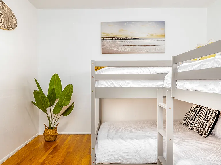 Hardwood floors, a cozy rug, and natural greenery create a warm, inviting atmosphere. Wake up to sunlight streaming through the windows, and enjoy a space that feels like a getaway within your getaway. Perfect for creating unforgettable memories!