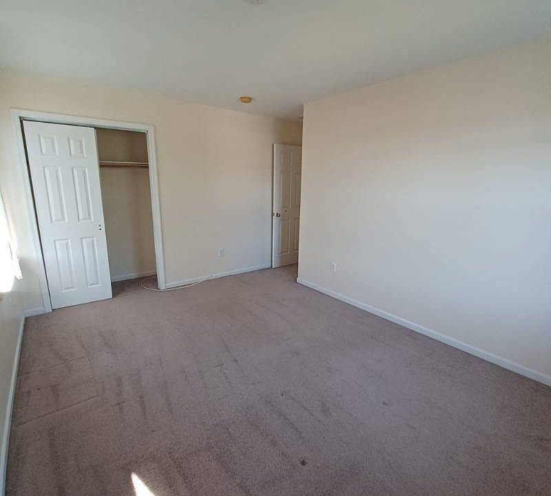 Another view of the bedroom highlighting the spacious closet and clean carpeting. The room feels open, quiet, and comfortable, ideal for rest and personal space.