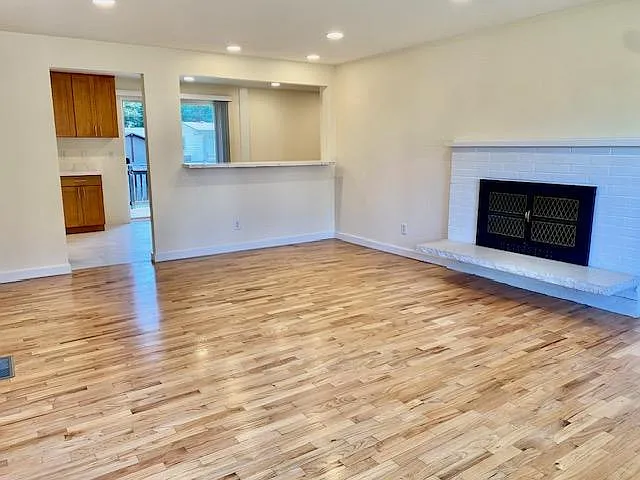 Living room with hardwood flooring and wood burning fireplace