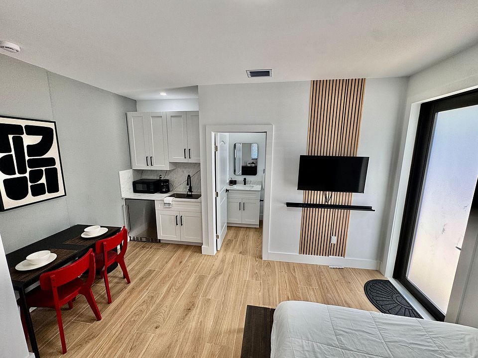 Efficient studio-style space with kitchenette, dining nook, and wall-mounted TV, plus a private vanity area off the hall.