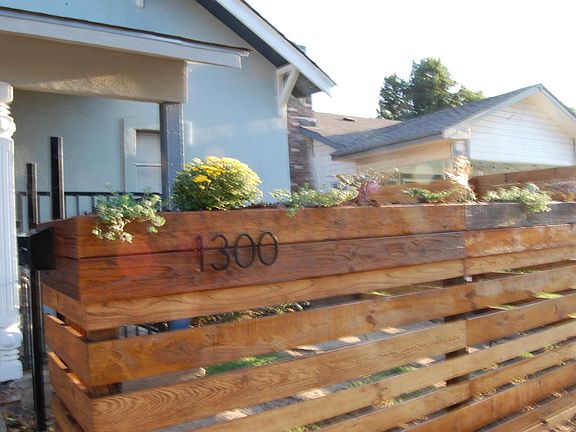 BRAND NEW custom built privacy fence in the front. Hand stained with a a planter top filled with cactus and mums.
