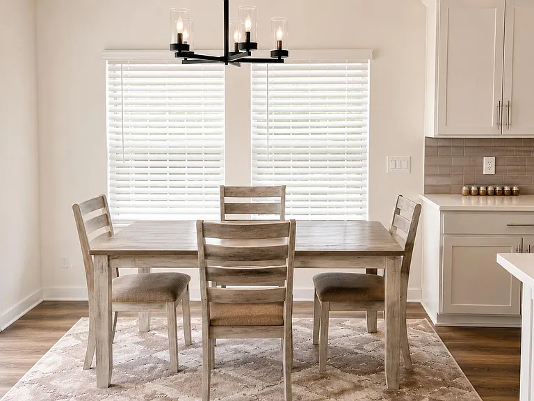 Eat-in dining area with a full-size table, stylish chandelier, and large windows plus a nearby patio door for easy outdoor ac