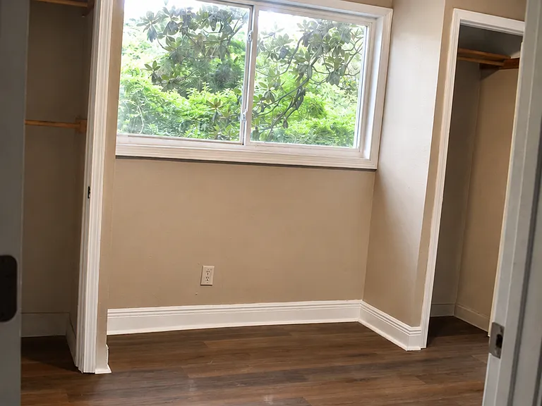 Cozy bedroom with large window, natural light, and dual closets for extra storage.