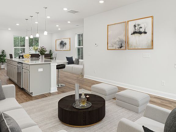 Living room with seating and island kitchen in a DRB Homes Brookgreen model home at the Park Circle