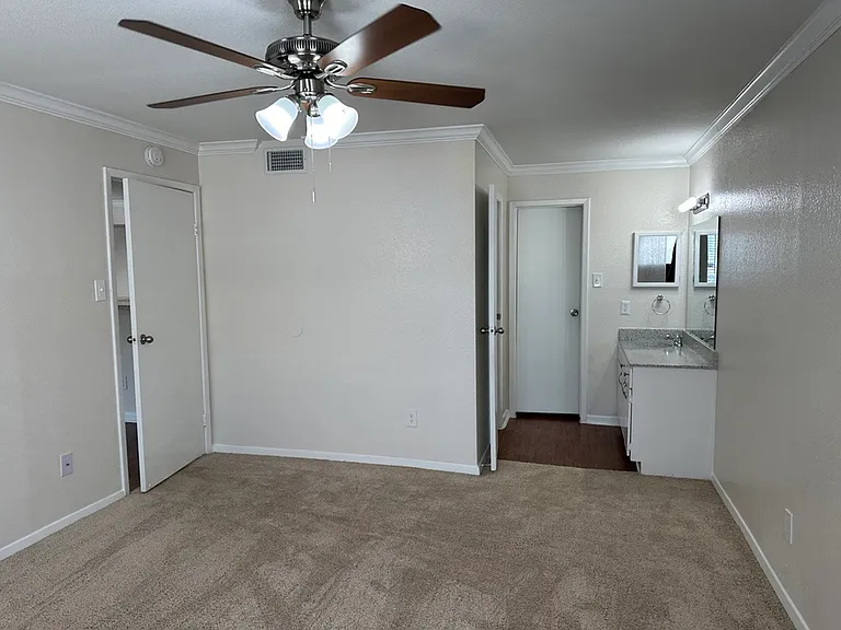 Inviting room with plush carpet, ceiling fan, and adjacent bathroom offering modern convenience and comfort. Inviting room with plush carpet, ceiling fan, and adjacent bathroom offering modern convenience and comfort.
