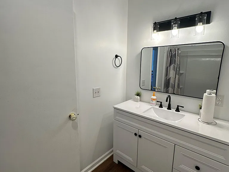 Updated bathroom with a wide vanity, ample drawer storage, and an oversized mirror with modern lighting.