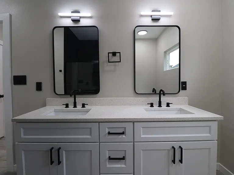 Modern primary bathroom featuring double vanity with quartz countertops, sleek fixtures, and excellent lighting. Clean, contemporary design.
