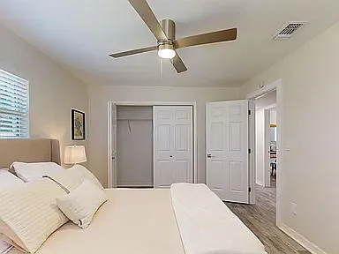 Spacious private bedroom with ceiling fan, large closet, natural light, and hardwood-style floors - 2006 E Hanna Ave