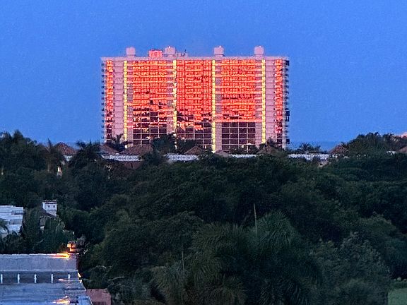 Setting sun reflecting on the west side of the building in the distant east.