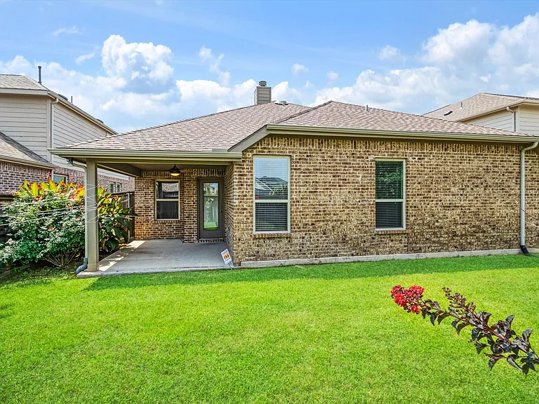 Expansive backyard featuring a covered patio with concrete flooring, a brick exterior, a shingle roof, and established landscaping