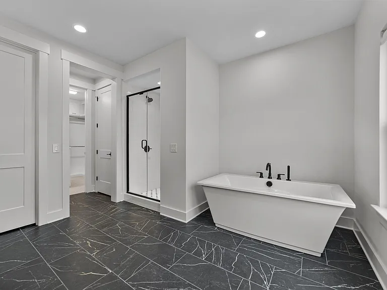 Soaking tub and walk-in shower leading to the custom closet