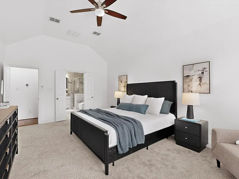 A spacious primary bedroom featuring a ceiling fan and an en suite bath.