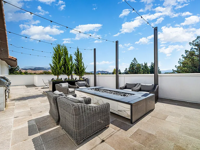 Rooftop terrace with lounge seating, firepit, and hillside views