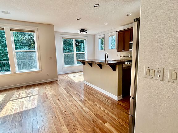 Sun-filled kitchen and living area with breakfast bar and tree views