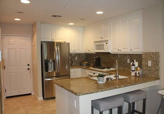 View from living area into kitchen. Door into garage. White fridge (not Stainless) included