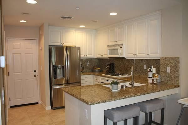 View from living area into kitchen. Door into garage. White fridge (not Stainless) included
