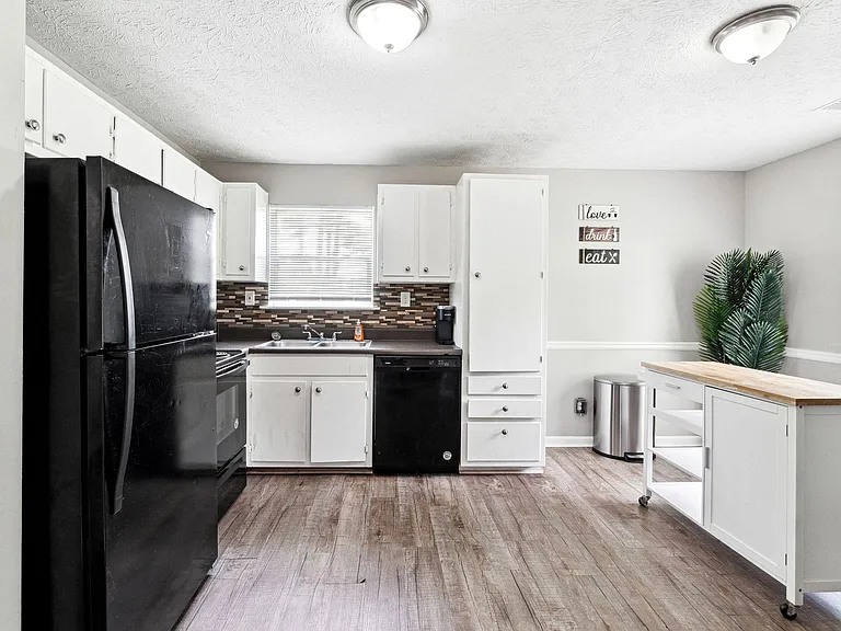 Functional eat-in kitchen with ample cabinet storage, full appliance suite, and a mobile butcher-block prep island.