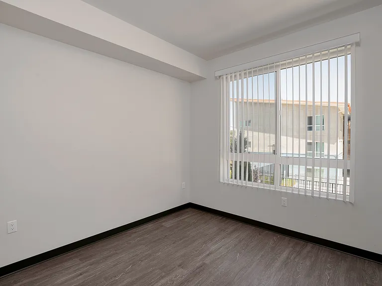 Bedroom A with a large window and a clean, versatile layout ready to make your own.