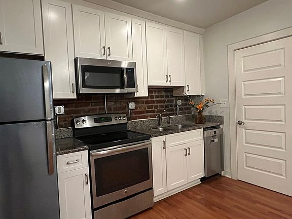 Exposed brick wall, granite counters, new white cabinets and stainless appliances make for a tidy kitchen!