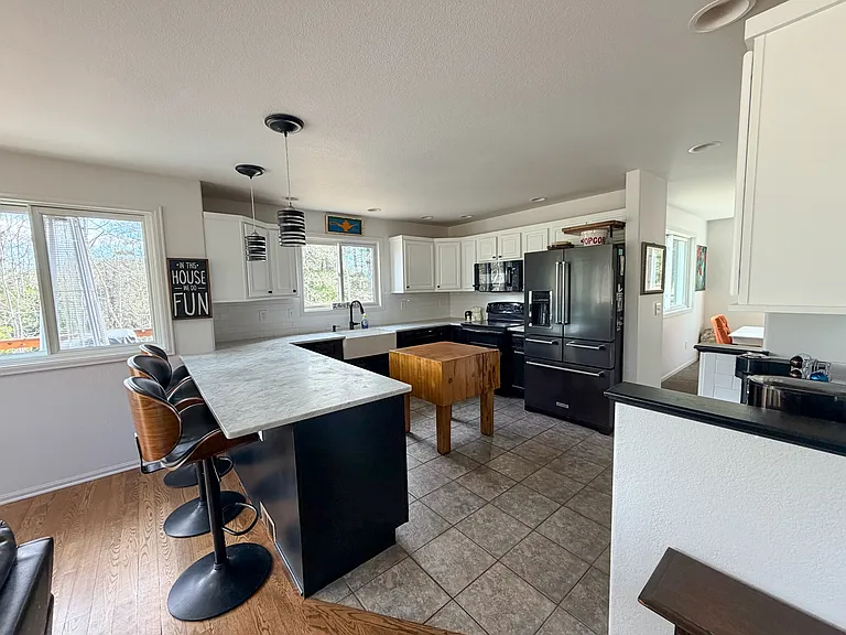 Open kitchen, tiled floor that leads into living space with hardwood floors