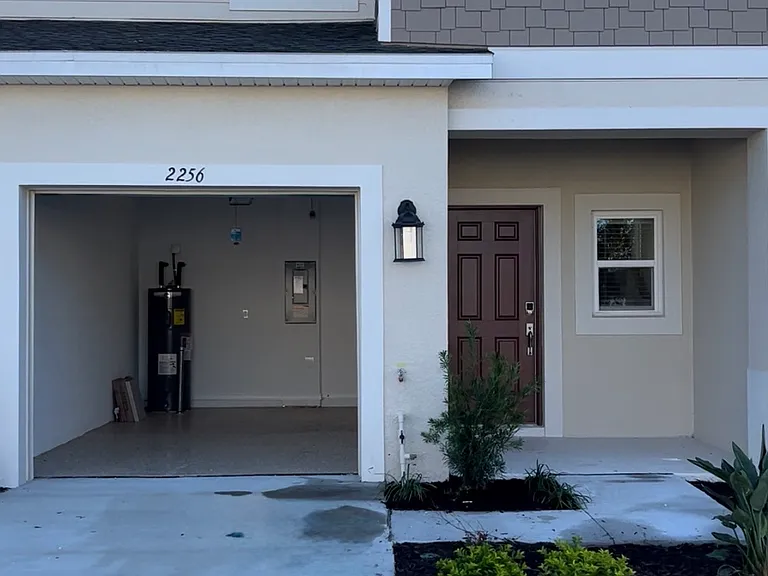 Outside entry, driveway and garage. Two story, middle unit.