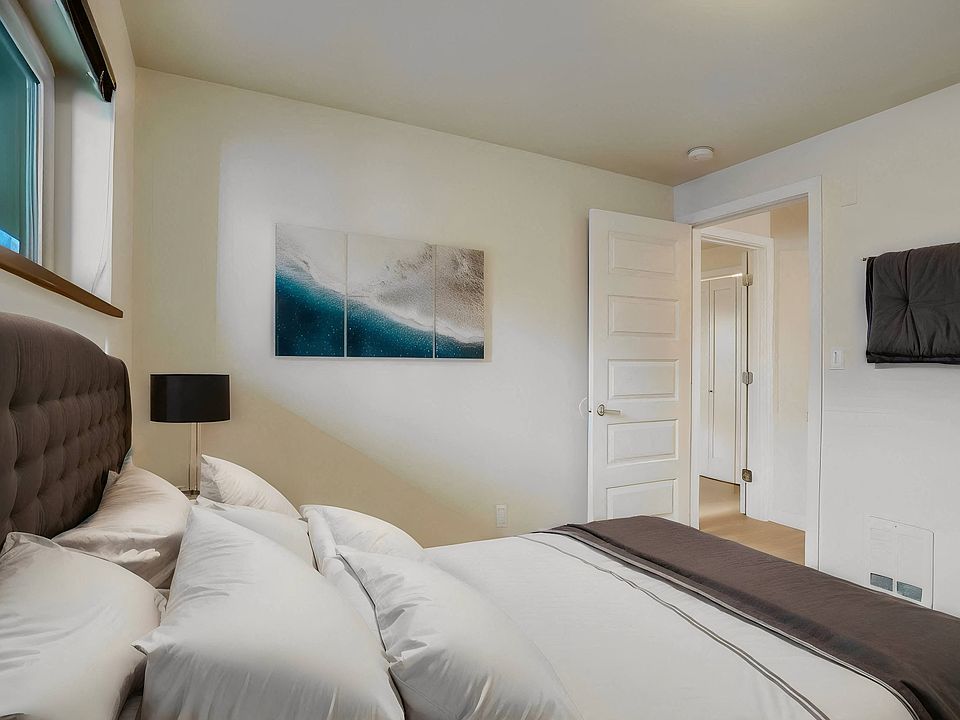 A cozy bedroom featuring a comfortable bed, natural light from the window, and a door leading to an adjacent room, offering a warm and inviting atmosphere.
