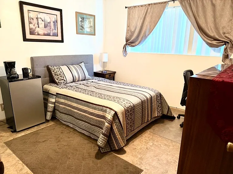 Bedroom bed with new bedding and pillows desk, small fridge, large dresser, nightstand, ceiling, fan, TV, free Wi-Fi, mirrored closet with shelves and rods for hanging clothes, blackout curtains.