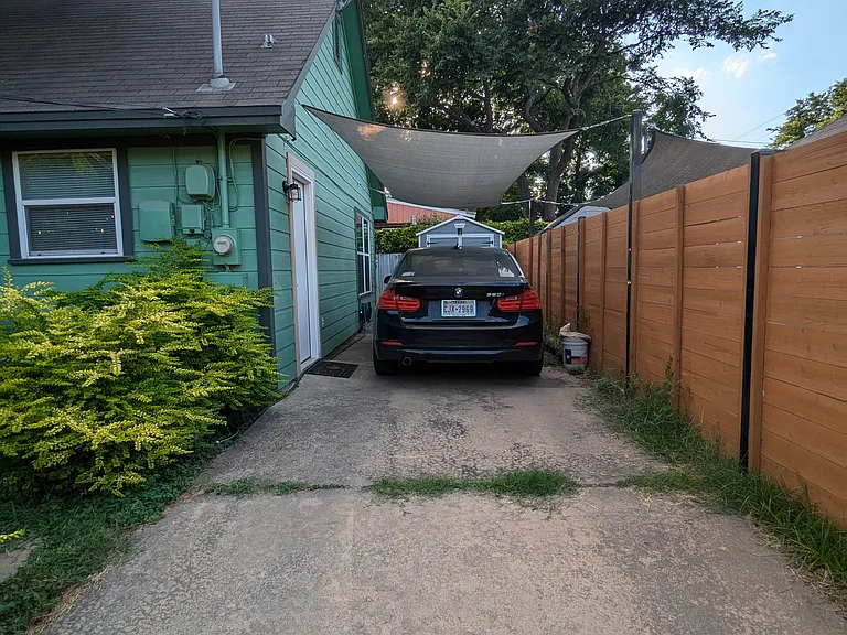 Car port with shade sail in the back of the house. Shed is behind the carport