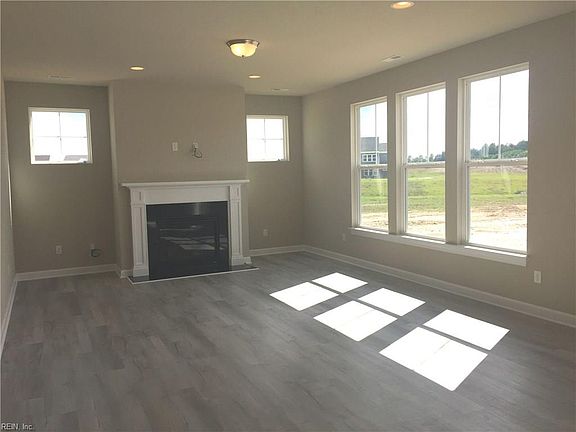 Light filled greatroom with gas fireplace, black granite surround and hearth, recessed can lights and pre-wired for ceiling fan