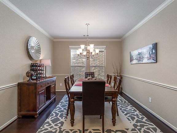 Lovely formal dining room featuring hardwood flooring, crown & chair rail molding, and chandelier is sure to be a gathering spot and many memories will be made with friends and family!