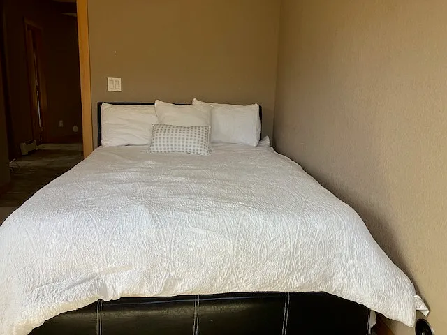 View of queen bed from dresser/window