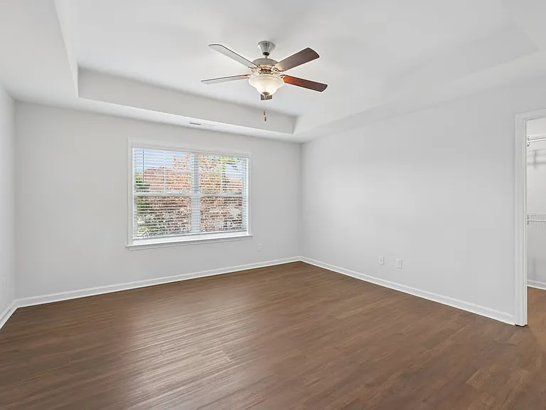 Classic Package Primary bedroom with ceiling fan, walk-in closet, and hard-surface vinyl plank flooring (in select homes)