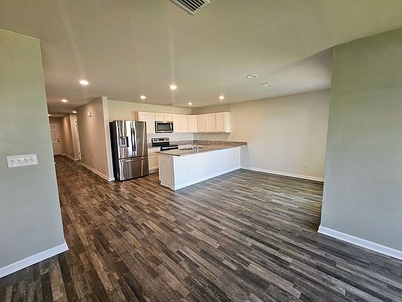 View from living room into kitchen. All kitchen appliances on site. Recessed lighting throughout house