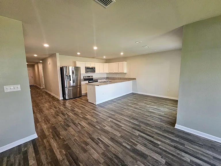 View from living room into kitchen. All kitchen appliances on site. Recessed lighting throughout house