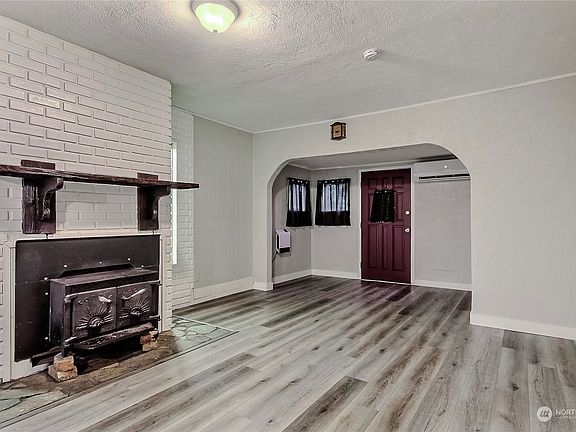 View from living room to entry, I love the wood fireplace, the flooring, and the character is this home.>