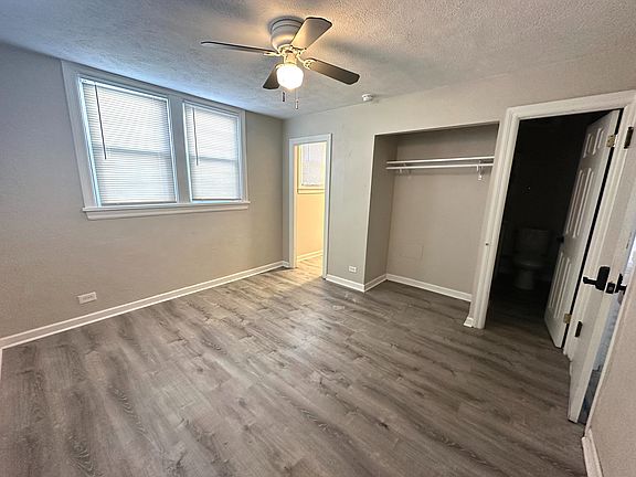 Bright, spacious bedroom with elegant wood flooring, ceiling fan, and ample natural light filtering through large windows.