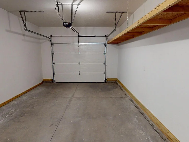 View from laundry room into oversized single car garage with Overhead storage