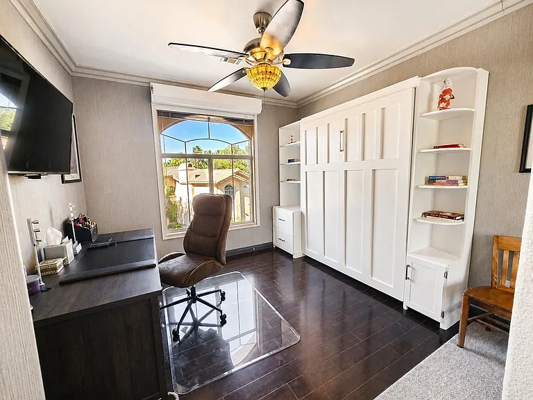 Flexible room with built-in wall bed, desk workstation, and ample shelving, plus a large window for natural light.