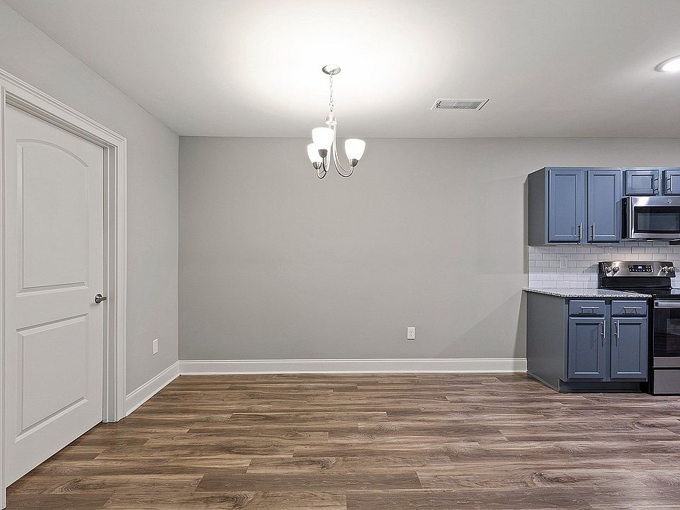 Modern kitchen & dining space with sleek blue cabinetry and stainless steel appliances, complemented by elegant wood flooring and a stylish overhead chandelier.