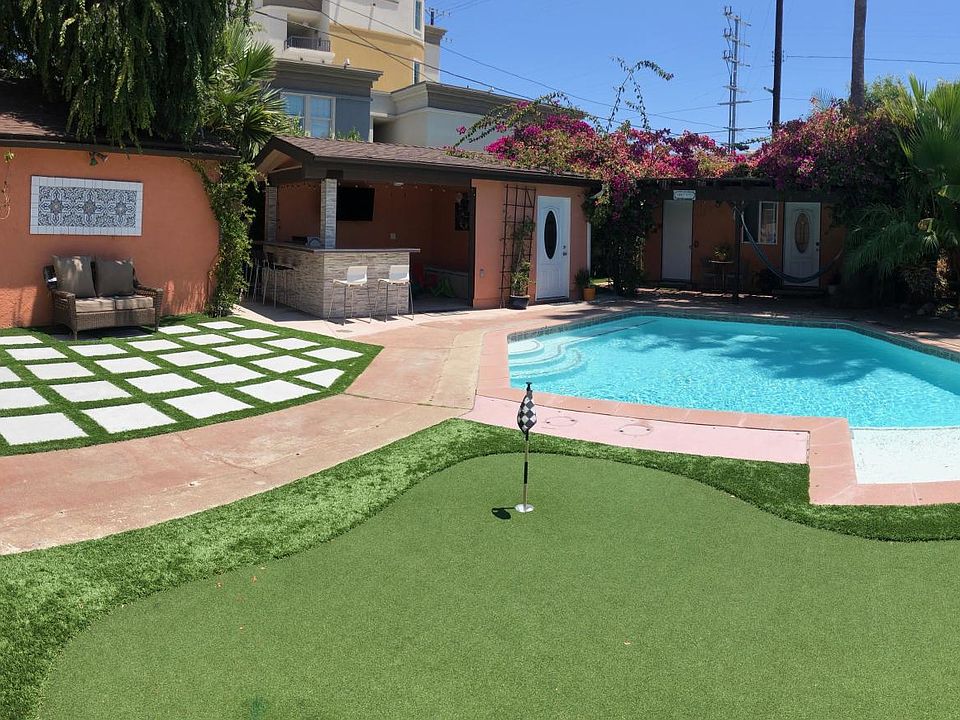 Backyard oasis with Cabana, Heated Pool, Putting Green, Pool Guest House, Pool Shower/bathroom, Shade areas, built in grill, built in booth style seating, full TV/internet.