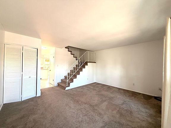 Large and bright living room with carpet. A jacket closet in the corner.