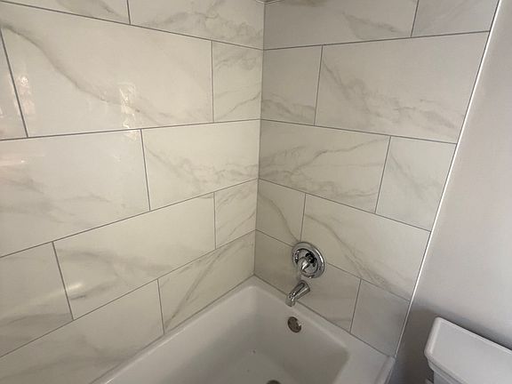 Remodeled Bathroom - new tub, tile walls, tile flooring, new toilet, vanity, mirror. New bathroom.