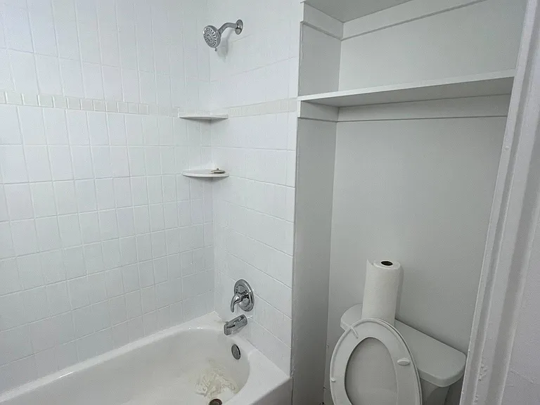 Updated bathroom featuring a newly tiled shower surround and bathtub.