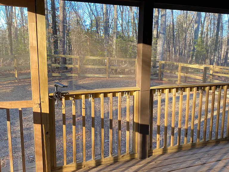 Back porch is screened in with two rocking chairs. Wooded area all around for a peaceful environment.
