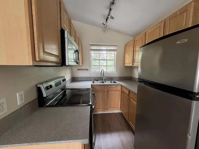 Efficient galley kitchen with ample cabinet storage, laminate countertops, double-basin sink, and full-size appliances.