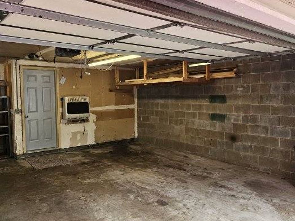 Right side of garage with suspended storage shelf and basement door entry.