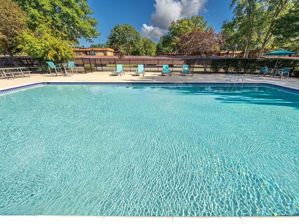Heated pool equipped with comfy lounge chairs at Westwood Village Apartments in Westland, MI