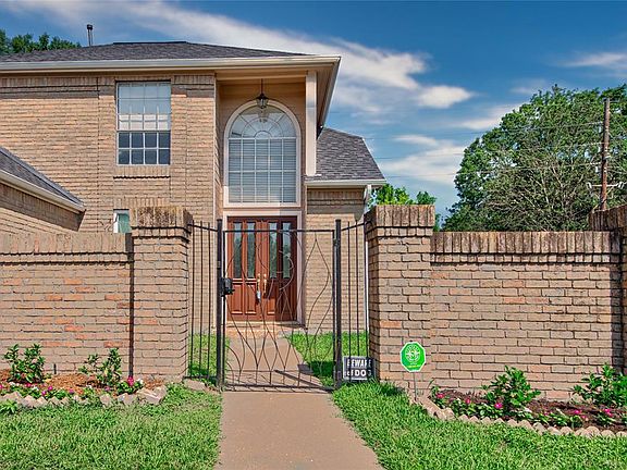 Gated walled courtyard entry to double front doors into home. Olive tree in the courtyard rocovering from the freeze.